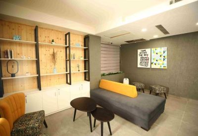 Lounge area with a grey and yellow modular sofa and wooden wall shelving.