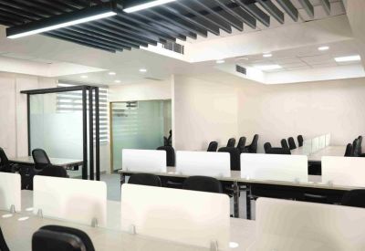 Open-plan office with rows of white desks and black mesh chairs.