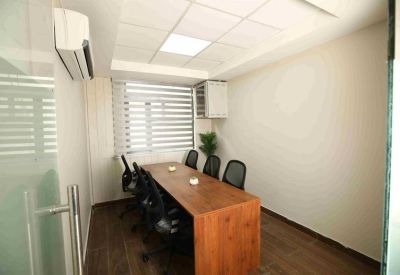 Private six-person meeting room with a wooden table and glass entrance.