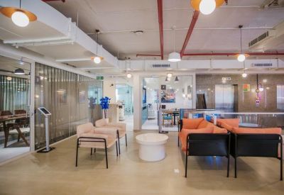 Modern reception and lounge area with soft peach armchairs and warm overhead lighting.