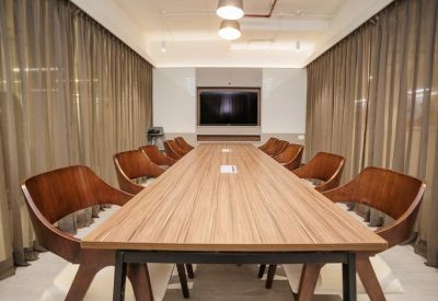 Professional meeting room featuring a long wooden conference table and sheer curtains.