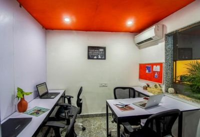 Small office suite with white desks, black chairs, and bright orange ceiling accents.