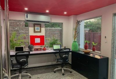 Dual-workstation office with a long desk, laptops, and a red feature wall panel.