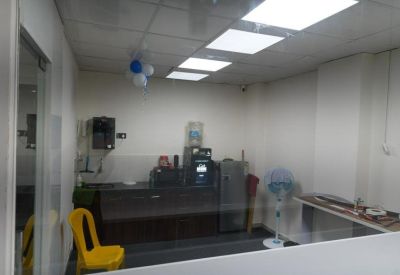Compact communal kitchen area with a coffee machine, water dispenser, and a yellow chair.