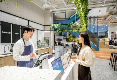 Modern cafe area with a barista counter, pendant lighting, and hanging greenery.