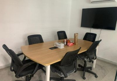 Modern meeting room featuring a wooden table, several black chairs, and a wall-mounted TV.