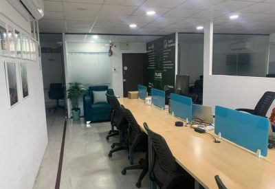 Long communal desk with vibrant blue privacy screens and a row of black office chairs.