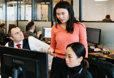 Close-up of a collaborative workspace with people working at desktop computers.