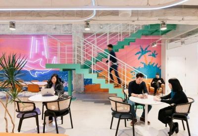 Bright coworking area featuring colorful wall murals, a green staircase, and modern seating.
