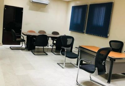Conference room with a wooden table, several black mesh chairs, and dark blue acoustic wall panels.