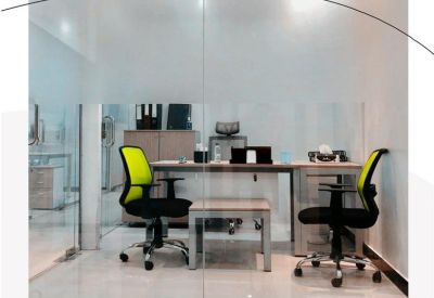 Glass-walled office suite with bright lime green mesh chairs and a minimalist desk setup.