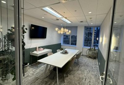 Professional boardroom featuring a long white table, globe light fixture, and dark green accents.