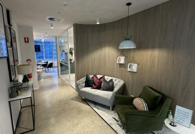 Waiting area with a grey sofa, velvet armchair, and warm wooden feature wall.