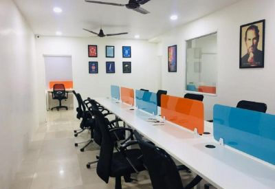 Long white communal coworking desk with vibrant orange and blue privacy screens.