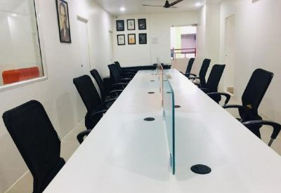 Bright boardroom featuring a long white conference table and black executive chairs.