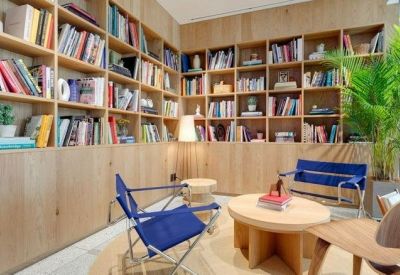 Cozy library nook with floor-to-ceiling wooden bookshelves and blue folding chairs.