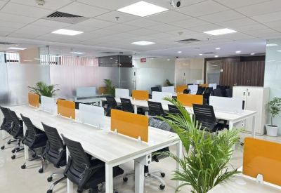 Bright open-plan workspace featuring rows of white desks with orange and grey privacy screens.