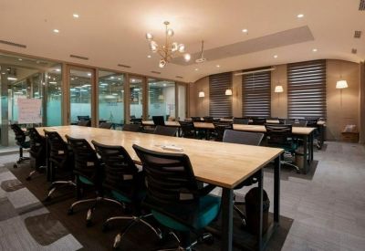 Brightly lit conference room with a long wooden table and glass partitions.