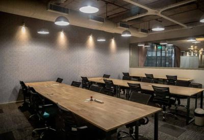Long wooden shared tables under warm pendant lighting in a modern industrial-style office.