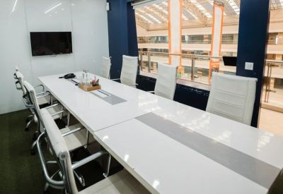 Professional meeting room featuring a long white conference table and ergonomic chairs.