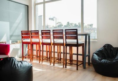 Casual seating area with wooden bar stools facing a window and black bean bags.