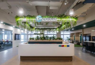 Branded white reception desk with lush greenery hanging from a lighted ceiling fixture.
