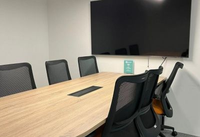 Small conference room featuring a wall-mounted TV and orange upholstered chairs.