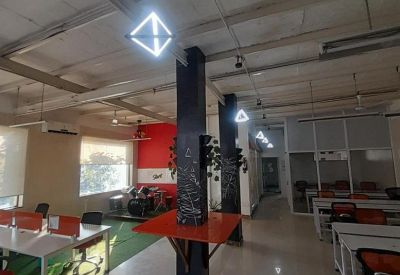 Industrial style office floor with geometric pendant lights and orange desk accents.