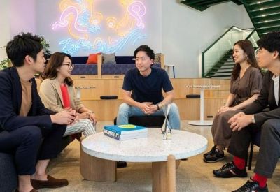 Group of colleagues having an informal discussion in a bright lounge with colorful wall art.