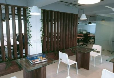 Communal breakout area with glass-top tables, white chairs, and decorative wooden slat partitions.