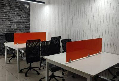Workspace with rows of white desks, orange dividers, and modern linear pendant lighting.