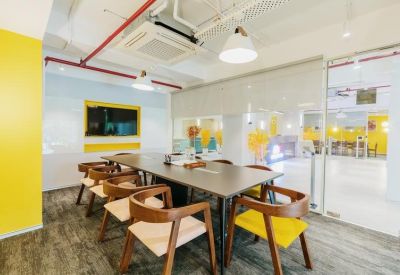 Modern glass-walled meeting room with a dark wood table and yellow accent chairs.