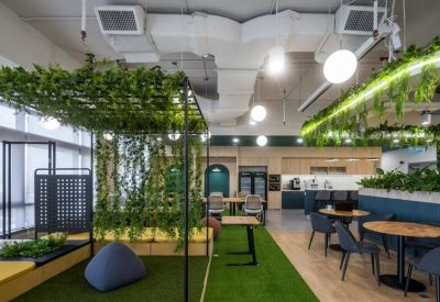 Breakout lounge with artificial grass flooring, a plant-covered pergola, bean bags, and cafe seating.