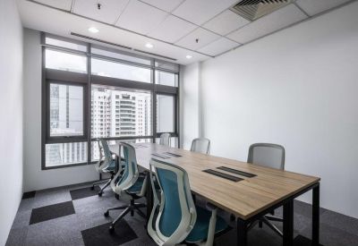 Bright private meeting room with a wooden table, ergonomic blue chairs, and large windows with city views.