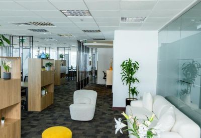 Bright breakout area with a white sofa, yellow stool, and modern decor.