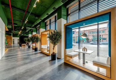 Spacious corridor with built-in seating nooks and indoor trees under a green industrial ceiling.
