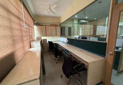 Narrow office area with a long desk against a window wall and black office chairs.