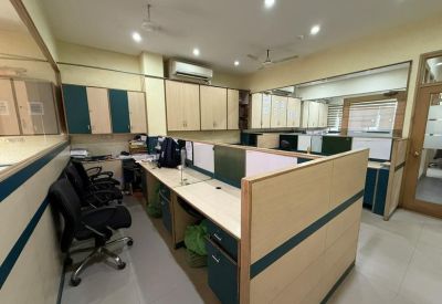 Brightly lit office suite with L-shaped desk partitions and overhead cabinets.