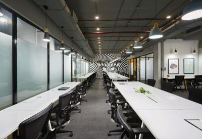 Spacious shared workspace featuring long white tables and an accent wall with a geometric mural.