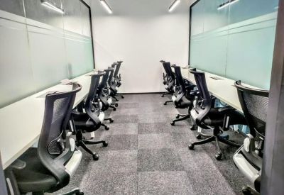 Modern office space with two rows of ergonomic black chairs and privacy glass partitions.