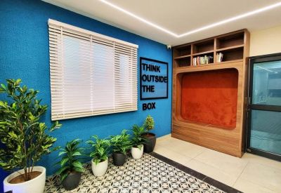 Bright communal lounge with a blue accent wall, indoor plants, and a wooden 'Think Outside The Box' display.