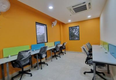 Open-plan workspace featuring orange walls, rows of desks with colorful dividers, and ergonomic chairs.