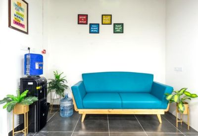 Lounge area with a vibrant blue sofa and water dispenser against a white wall.