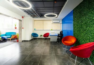 Lobby area featuring colorful seating, a greenery wall, and striped window blinds.