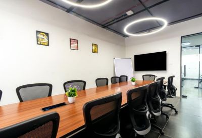 Spacious boardroom with a long wood table, black mesh chairs, and circular pendant lights.