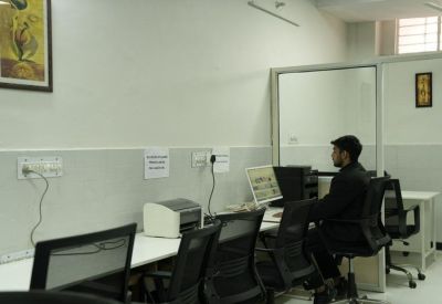 Individual workstation area with a printer and a professional working on a desktop computer.