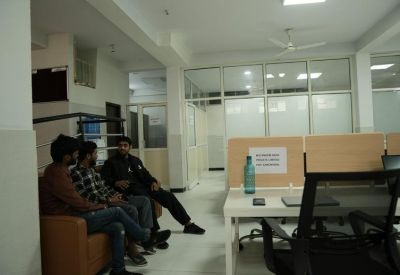 Lounge area with a brown leather sofa and workers seated in a bright, open communal space.