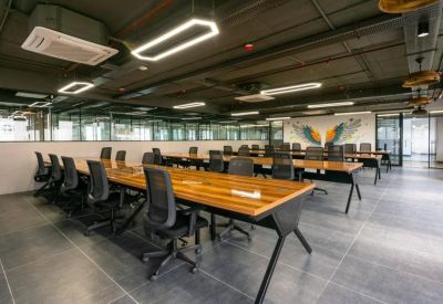 Coworking area with long wooden tables, ergonomic chairs, and a colorful mural in the background.