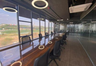 Professional boardroom with a long polished wood table, ring pendant lights, and floor-to-ceiling windows.