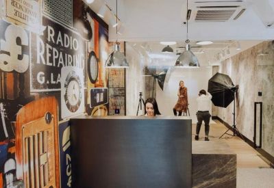 Reception area with a dark minimalist desk and a photography studio in the background.